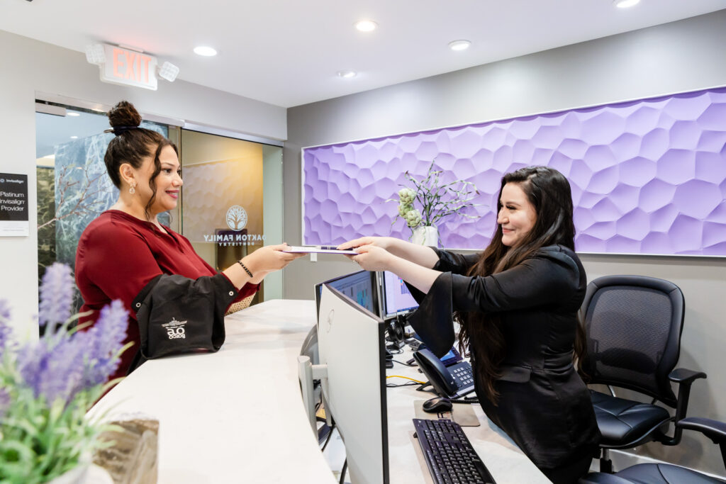 Front desk receptionist handing forms to a patient at our Fairfax dentist office